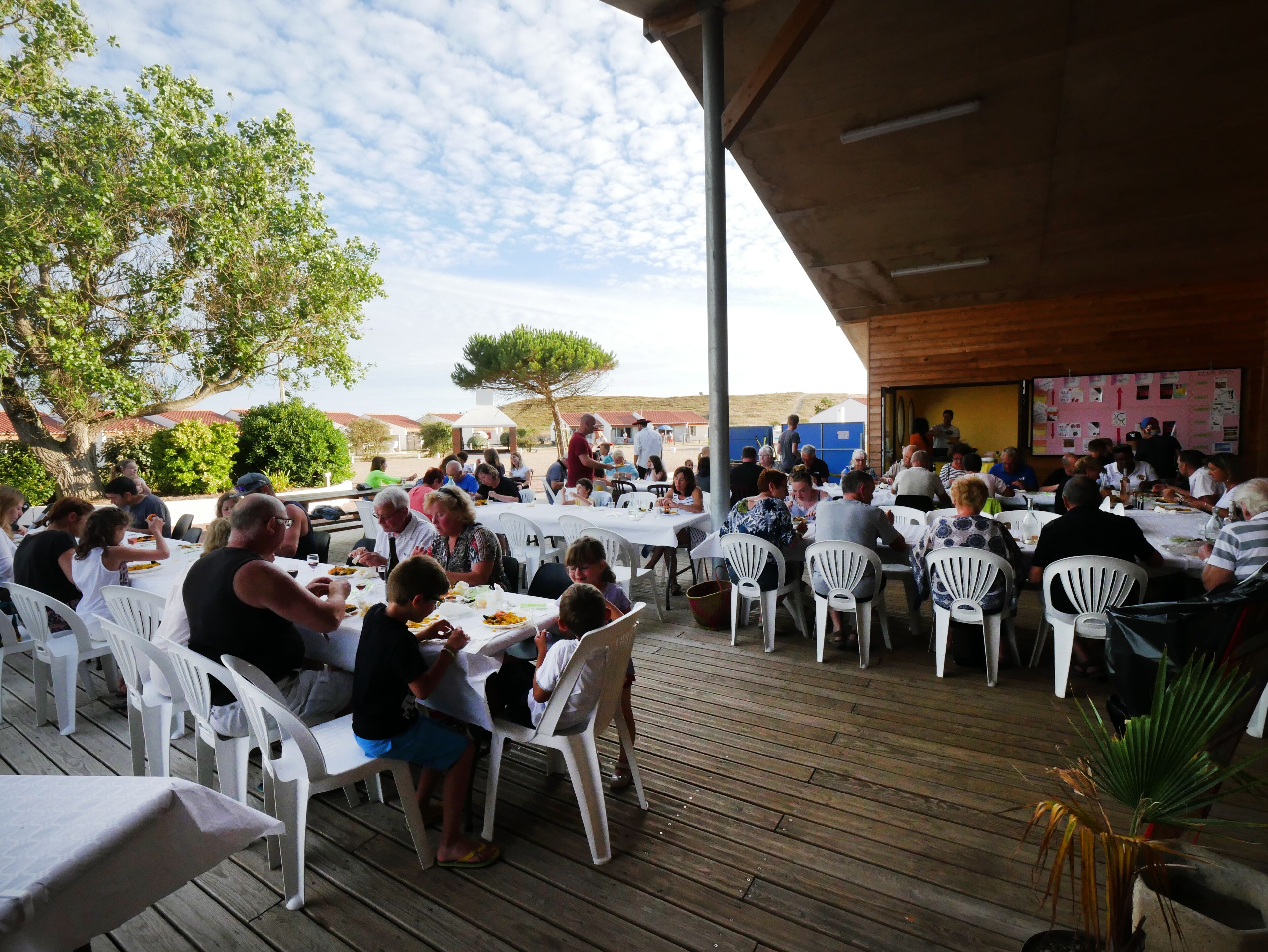 An outdoor dining area with tables and chairs, surrounded by trees and buildings.