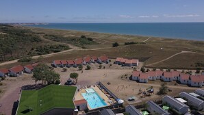 A coastal resort with multiple bungalow-style accommodations, a central swimming pool, and a view of the sea. - La Grande Dune - Vacances ULVF (Saint-Hilaire-de-Riez)