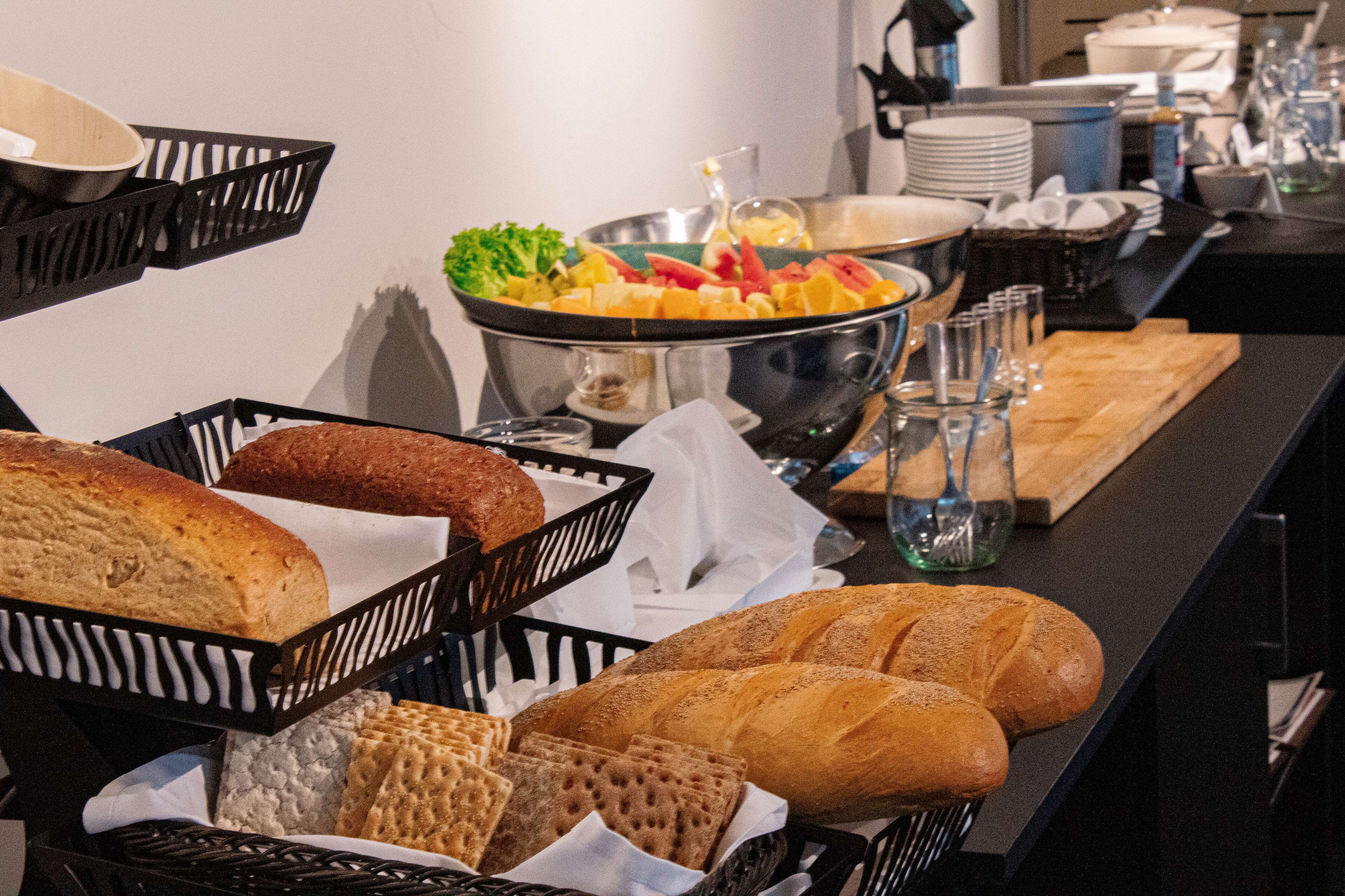 A buffet table with various breads and a fruit bowl.