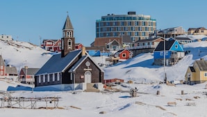 Un paysage enneigé avec des bâtiments, dont une église et un immeuble d’appartements moderne.