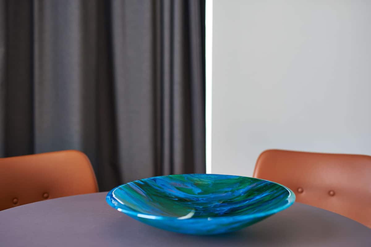 Eine blaue Glaskugel auf einem runden Tisch mit dunkler Oberfläche.