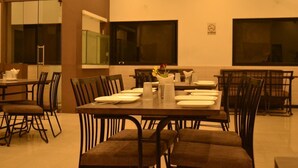 Un espace repas avec plusieurs tables et chaises, un vase rempli de fleurs et un panneau «interdiction de fumer» accroché au mur.