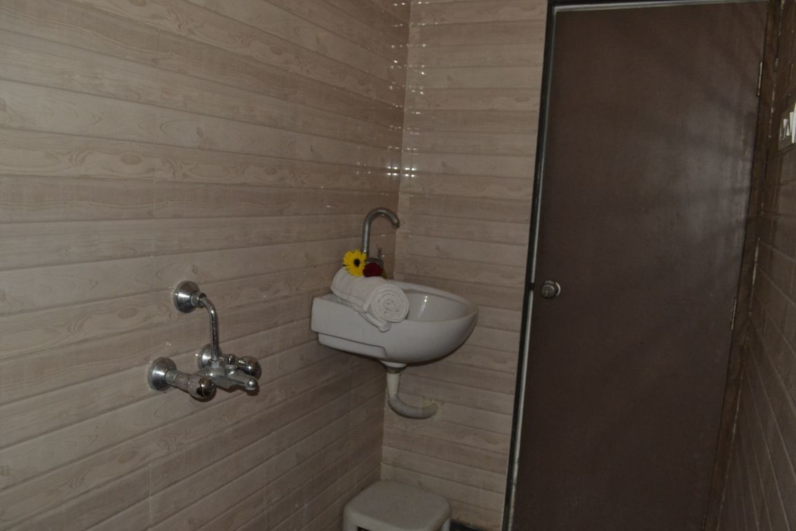 A bathroom with a wooden wall, a white sink, a towel, and a shower.