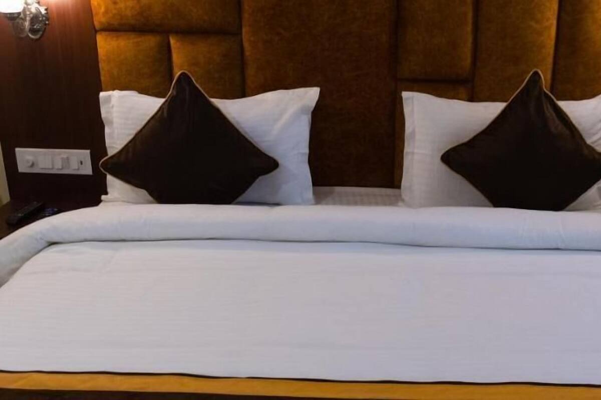 A bed with white bedding, two dark pillows, and a wooden headboard.