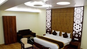 Una habitación de hotel con una cama, un sofá, una silla, un armario y un panel decorativo en la pared.