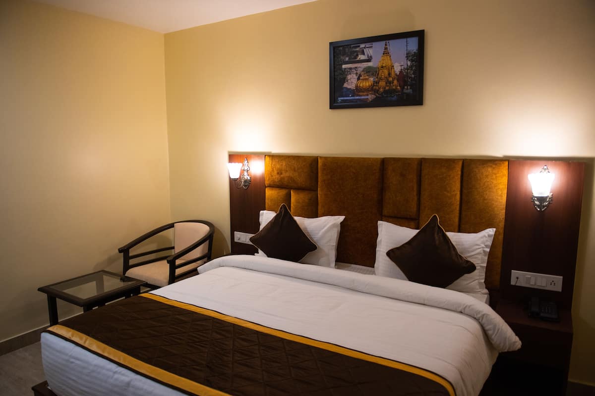 A hotel room with a large bed, two bedside tables, a chair, and a wall-mounted picture.