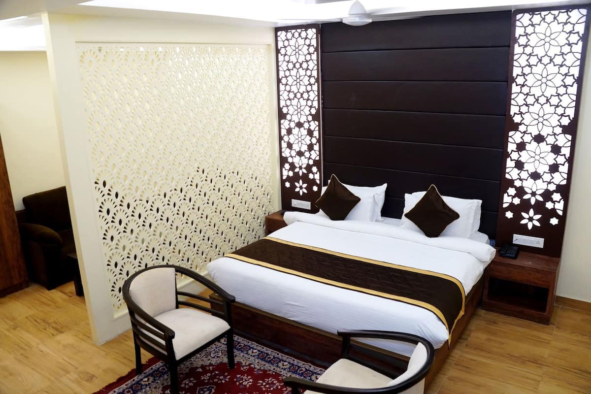 A bedroom with a bed, bedside tables, a chair, a decorative wall, and a patterned rug.