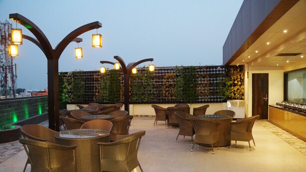 Terraza en la azotea con mobiliario de mimbre, luces colgantes y un muro verde con plantas.