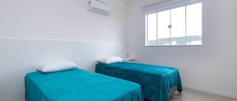 Una habitación con dos camas, una ventana y un equipo de aire acondicionado.