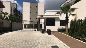 Un bâtiment moderne doté d’une entrée sécurisée par un portail, portant le numéro 1064, et d’une allée pavée menant à l’entrée.