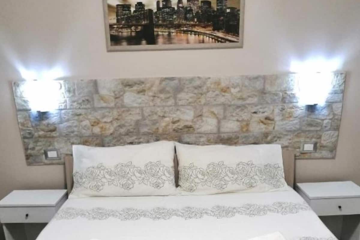 Ein ordentlich bezogenes Bett mit floralem Muster, zwei Kissen und zwei zusammengerollte Handtücher.