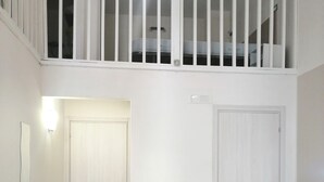 Un dormitorio con una cama, dos puertas, una escalera y una lámpara.
