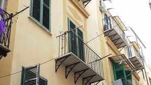Un edificio de varios pisos con balcones, contraventanas verdes y ropa tendida.
