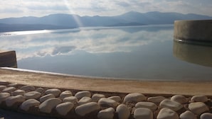 A calm lake with mountains in the background and a concrete structure in the foreground. - Modern, Family Friendly & Peaceful Villa with 15m long Infinite Private Pool & J (Theologos, Malesina)