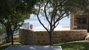 A stone wall with a table and chairs, a tree, and a view of the sea. - Modern, Family Friendly & Peaceful Villa with 15m long Infinite Private Pool & J (Theologos, Malesina)