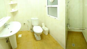 Un baño con lavabo, inodoro, bidé y cabina de ducha con mampara de vidrio.