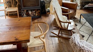 A cozy room with a stone wall, a fireplace, wooden furniture, and a view of greenery outside. - Savoyard Chalet Authentic (Saint-Martin de Belleville)