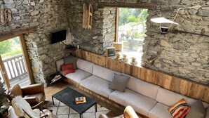 A cozy living room with a stone wall, a wooden bench, a sofa, and a coffee table. - Savoyard Chalet Authentic (Saint-Martin de Belleville)