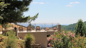 A modern outdoor patio with a seating area overlooking a scenic landscape.