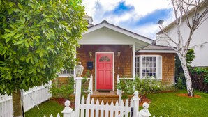 A house with a red door, white picket fence, and a well-maintained lawn. - A Touch of Cape Cod in West Hollywood (West Hollywood)