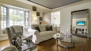 A modern living room with a glass coffee table, a sofa, and a television. - A Touch of Cape Cod in West Hollywood (West Hollywood)