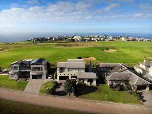 A residential area with houses, a golf course, and a view of the ocean.