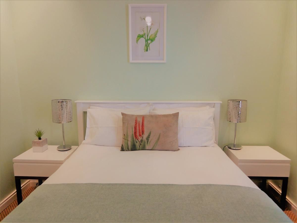 A neatly made bed with a single pillow, two bedside tables with lamps, and a framed picture on the wall.