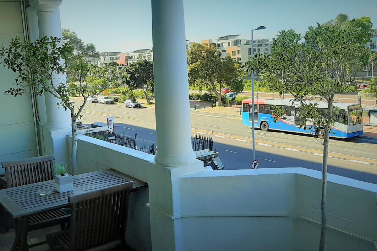 Ein Balkon mit Blick auf eine Straße, einen Bus und Gebäude im Hintergrund.