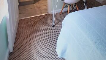 A hotel room with a shower, a desk with a chair, a bed, and a TV mounted on the wall.