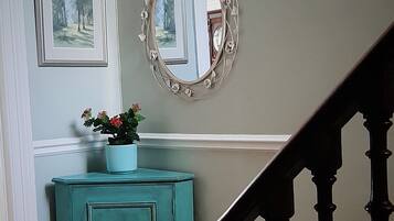 A staircase with a dark wooden handrail and a teal-colored cabinet with a potted plant.