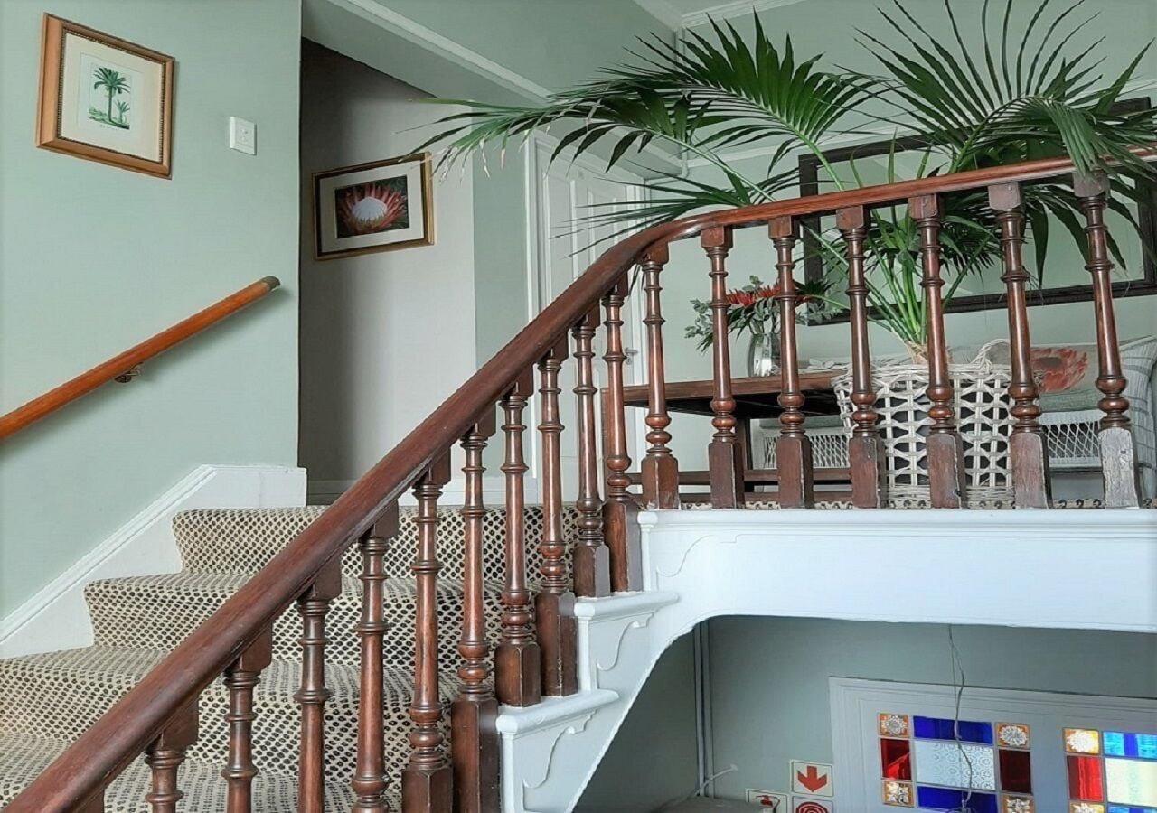 Una escalera de madera con barandilla blanca y un suelo estampado.