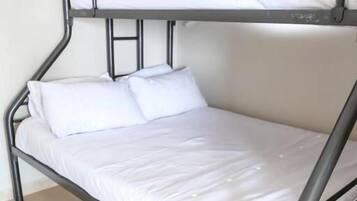 A bunk bed with white bedding in a room with tiled flooring.