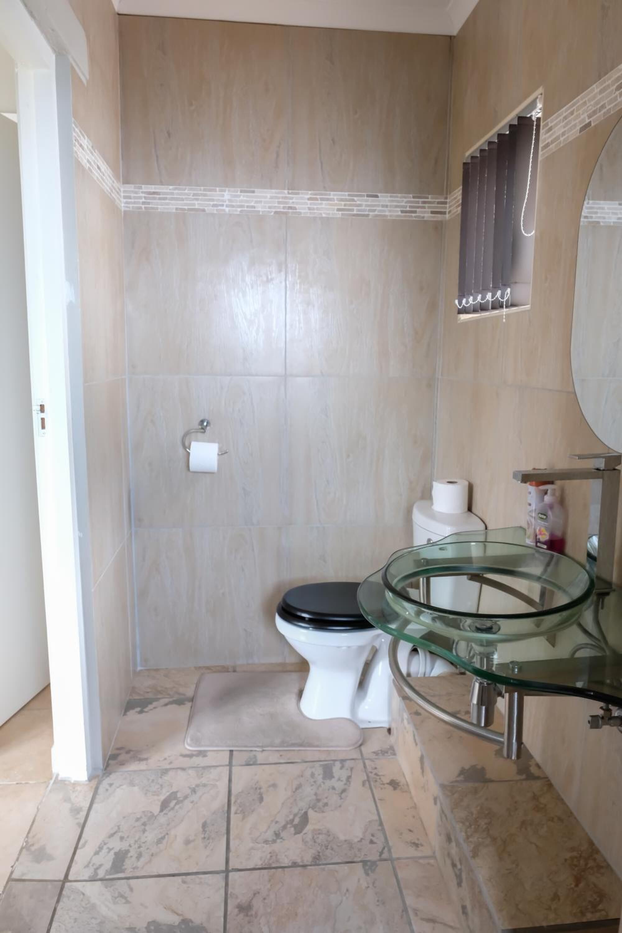 Une salle de bain avec des toilettes, un lavabo en verre et des murs carrelés.