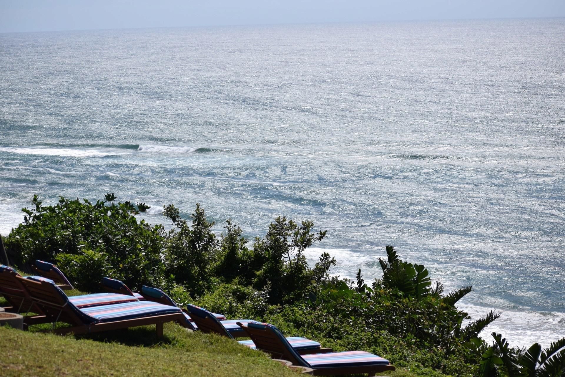 Vista de la playa con sillas de descanso y olas del océano.