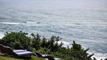 Vista de la playa con sillas de descanso y olas del océano.