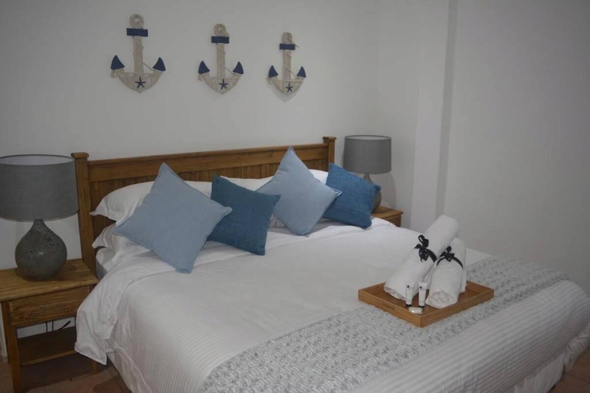 A neatly made bed with blue pillows, a wooden headboard, and a tray of towels.
