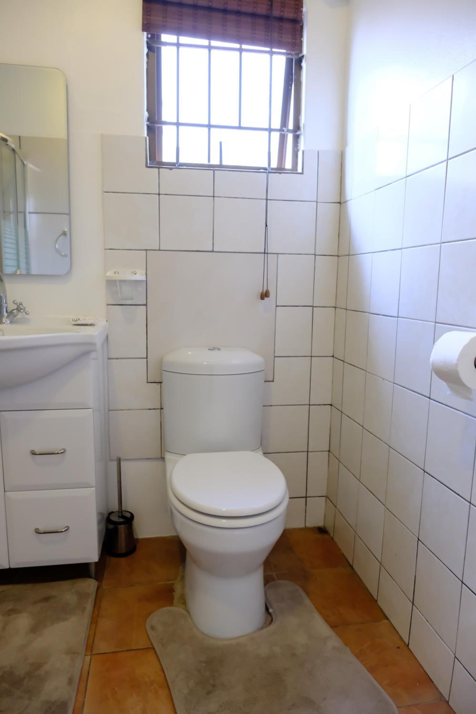 A small, clean bathroom with a toilet, sink, and mirror.