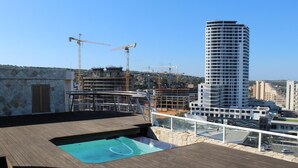 A rooftop pool area with a view of a cityscape, including a tall building under construction. - Unit 1101 Oyster Rock (Umhlanga)