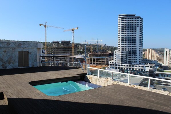 A rooftop pool area with a view of a cityscape, including a tall building under construction. - Unit 1101 Oyster Rock (Umhlanga)