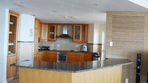 A modern kitchen with wooden cabinets, granite countertops, and stainless steel appliances. - Unit 1101 Oyster Rock (Umhlanga)