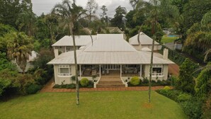 A large, two-story house with a covered porch and a landscaped garden. - Lemon Tree B&B (Kloof)