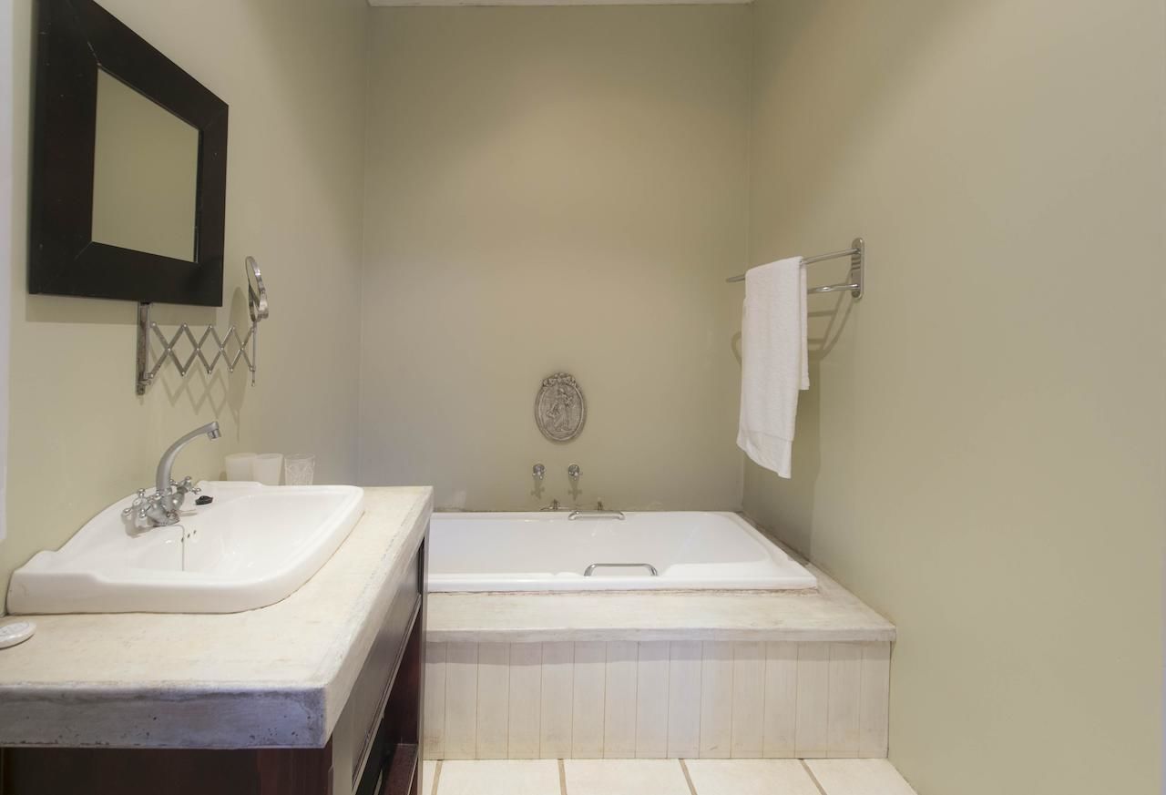 A bathroom with a sink, mirror, and bathtub.