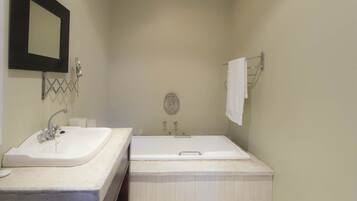 A bathroom with a sink, mirror, and bathtub.