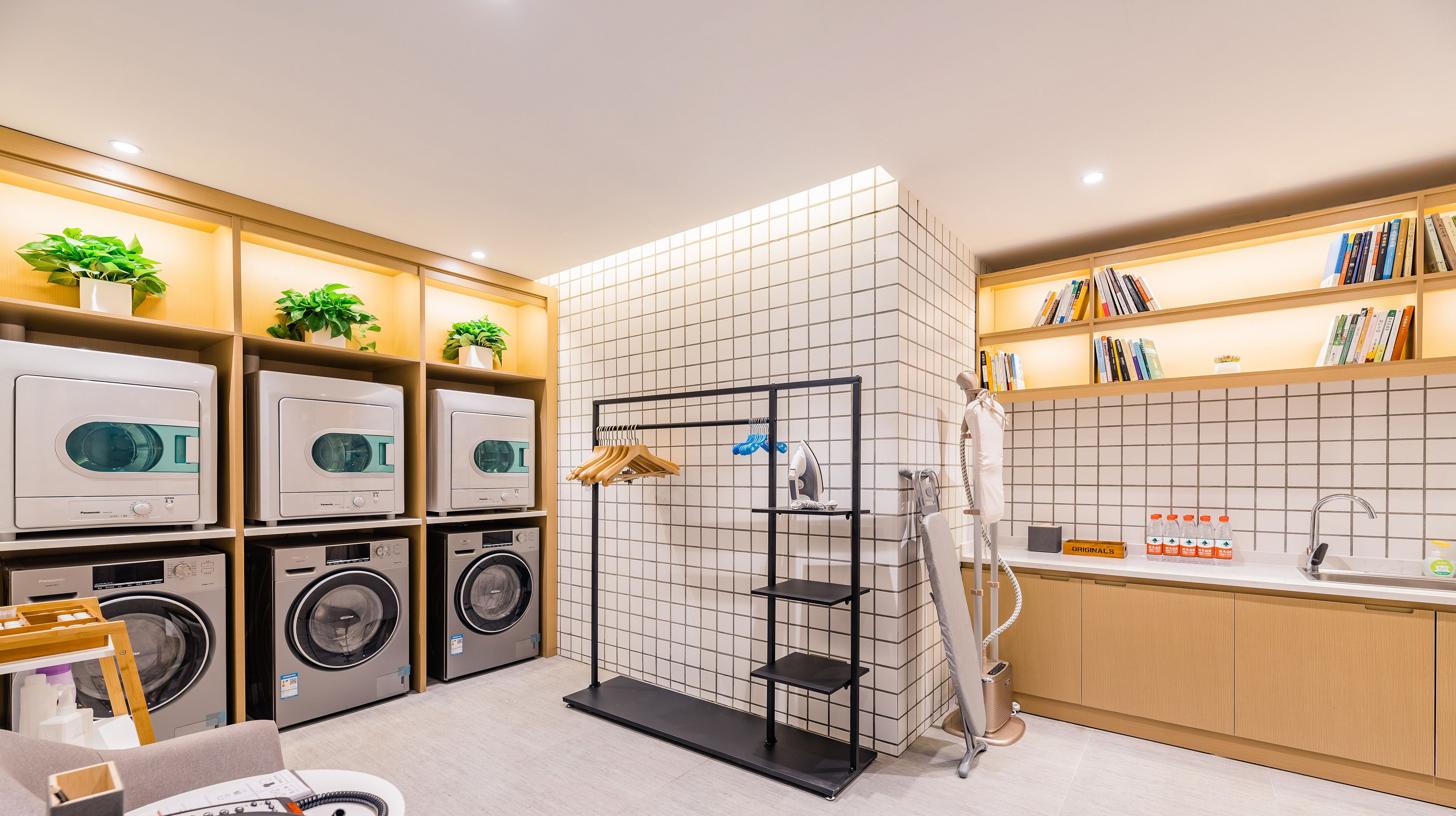 A modern laundry room with multiple washing machines, a drying rack, and a mannequin.