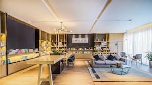 A modern living room with a central coffee table, a sofa, and a bookshelf filled with books and decorative items.