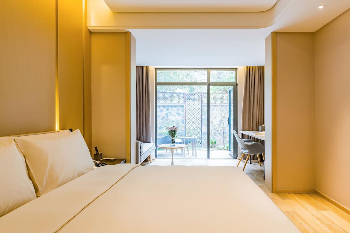 A hotel room with a large bed, a desk, and a view of the outdoors.