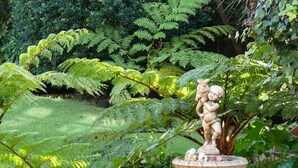 A garden with a stone fountain featuring a statue of a child holding a fish. - Aberdour Guesthouse (Gqeberha (Port Elizabeth))