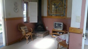 A living room with a fireplace, a television, and a chair. - Highland Rose Country House & Serenity Spa (Dullstroom)