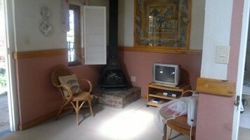 Uma sala de estar com lareira, televisão e uma poltrona.