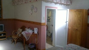 A room with a television, a chair, a small table, and a wardrobe.